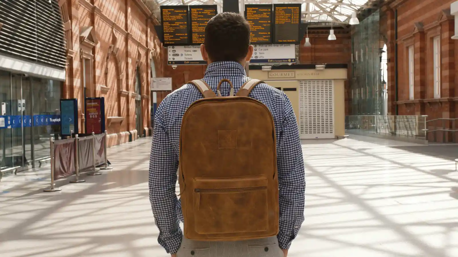 business man with his pack pack standing on a London train station looking at the time tables of arrival and departures